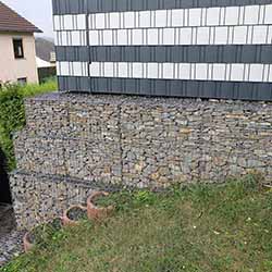 Gabionen als Stützwand mit aufgesetzten Zaun