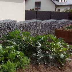 Steinkörbe abgestuft als Grundstückseinfassung im Garten